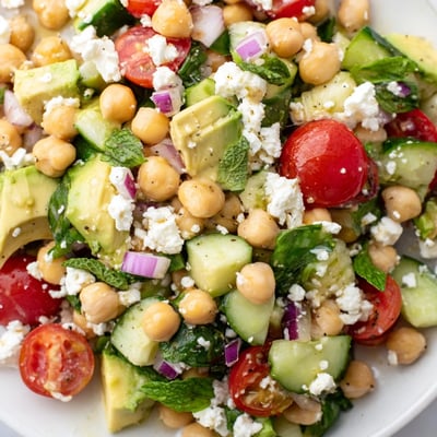 Crispy cucumbers and cherry tomatoes top this vibrant chickpea feta avocado salad platter